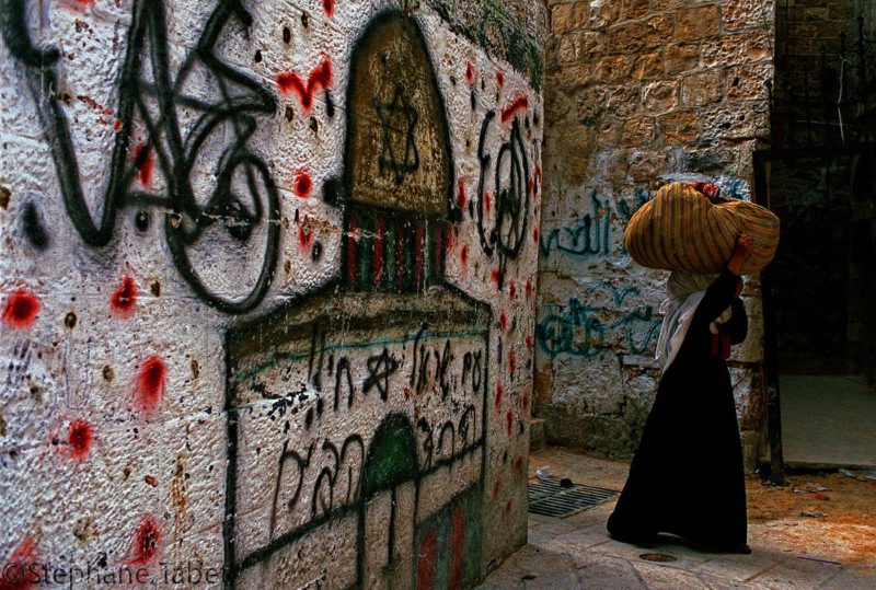 best travel photographers, A veiled woman and a drawing of the dom of the rock in Jerusalem Israel