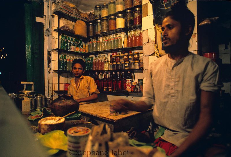 Two sellers in a smal shop at night in India