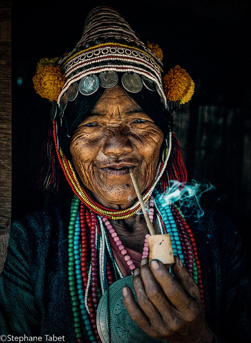 U Lo-Akha tribe old woman smoking pipe. North Thailand