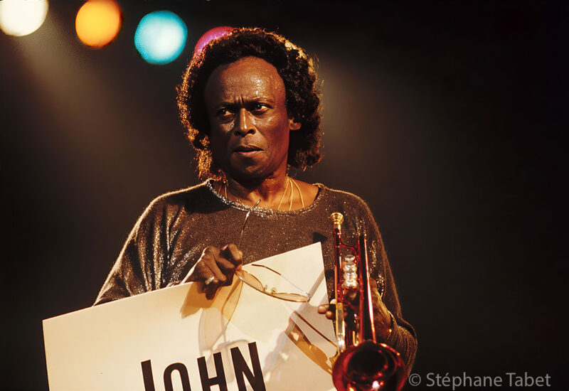 Miles Davis holding his trumpet and glasses